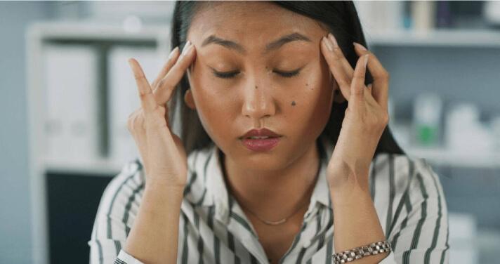 Woman experiencing long COVID symptoms, eyes closed, massaging her forehead. Woman experiencing long COVID symptoms, eyes closed, massaging her forehead.