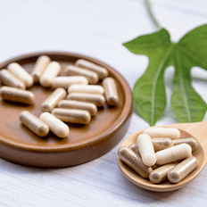 Herbal supplements on a wooden surface with a green leaf.