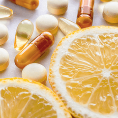 An orange with supplements in capsule, tablet and softgel form.
