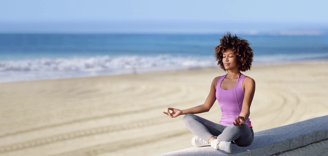 Mujer meditando en la playa sin preocupaciones.